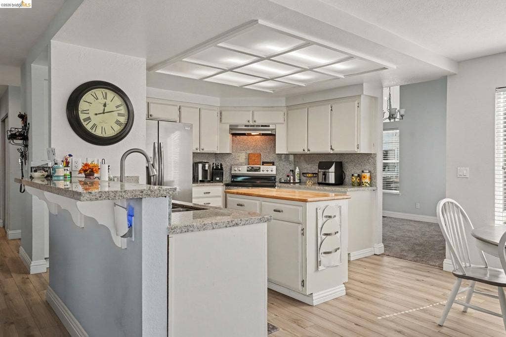 304 Greystone Dr, Antioch, CA 94509 Kitchen featuring stone-finish countertops, a center island with a wood-finish surface, recessed ceiling lighting, light-toned cabinetry, and wood-finish flooring