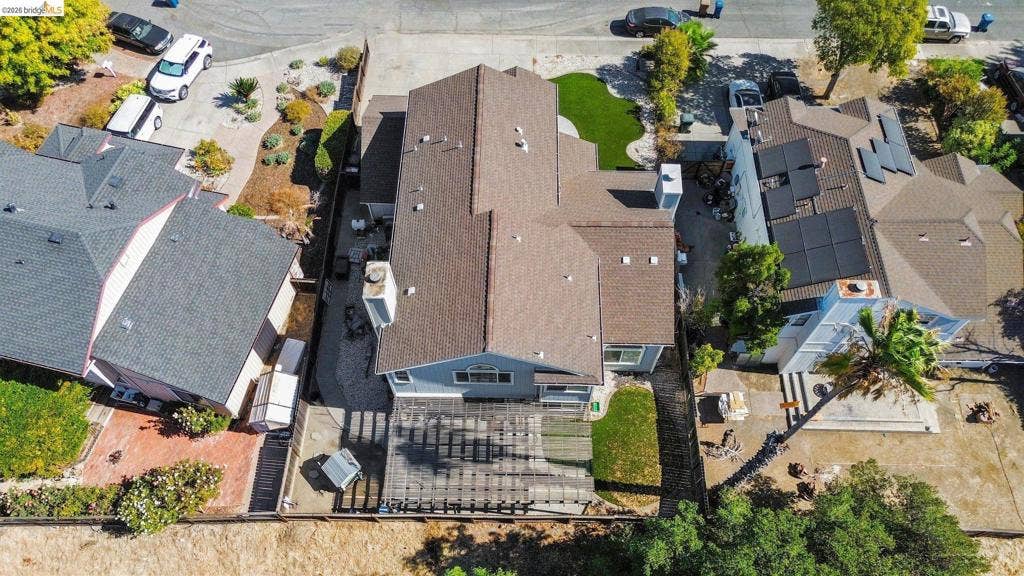 304 Greystone Dr, Antioch, CA 94509 Aerial perspective featuring a multi-pitched composition shingle roof, backyard wood pergola, manicured lawn, and two exterior masonry chimneys
