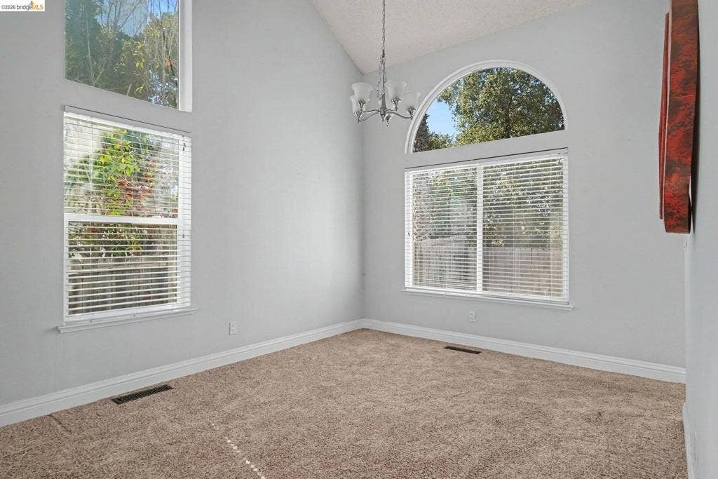 304 Greystone Dr, Antioch, CA 94509 Vaulted ceiling featuring a multi-light chandelier, expansive windows, and a prominent arched transom window
