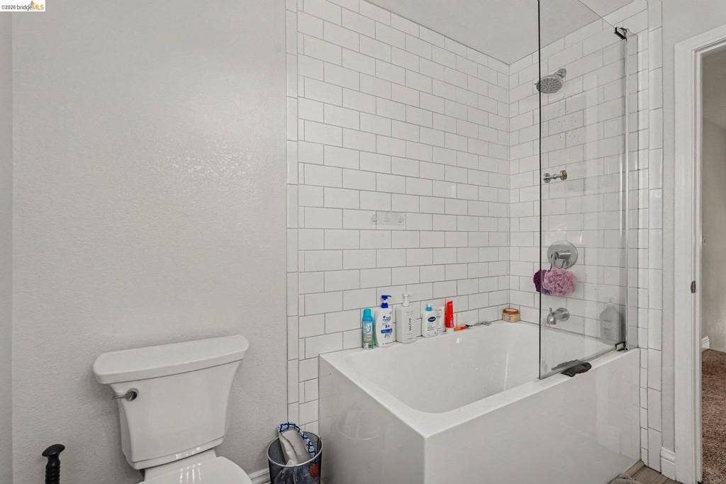 304 Greystone Dr, Antioch, CA 94509 Bathtub with a glass panel enclosure, white subway tile surround, wall-mounted shower head, and chrome fixtures