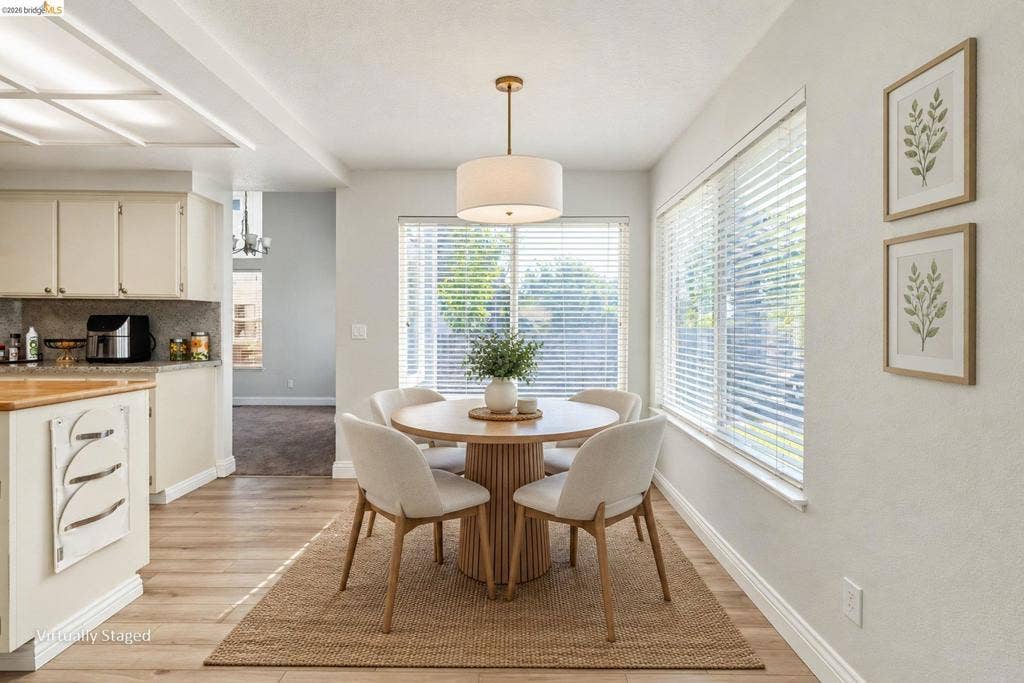 304 Greystone Dr, Antioch, CA 94509 Eat-in area featuring wood-finish flooring, a drum pendant light fixture, and horizontal blind window treatments