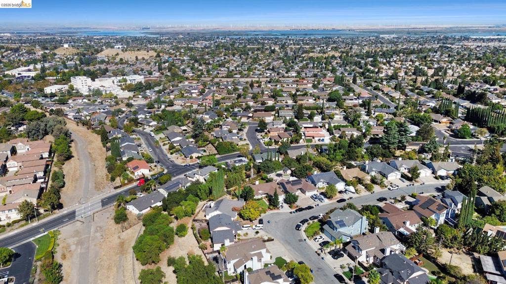 304 Greystone Dr, Antioch, CA 94509 Aerial perspective of a suburban neighborhood featuring winding residential streets, mature canopy trees, and proximity to expansive open water