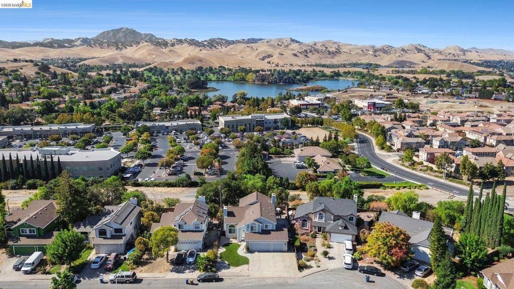 304 Greystone Dr, Antioch, CA 94509 Aerial perspective showcasing a residential neighborhood with mountain scenery, a local lake, and mature landscaping