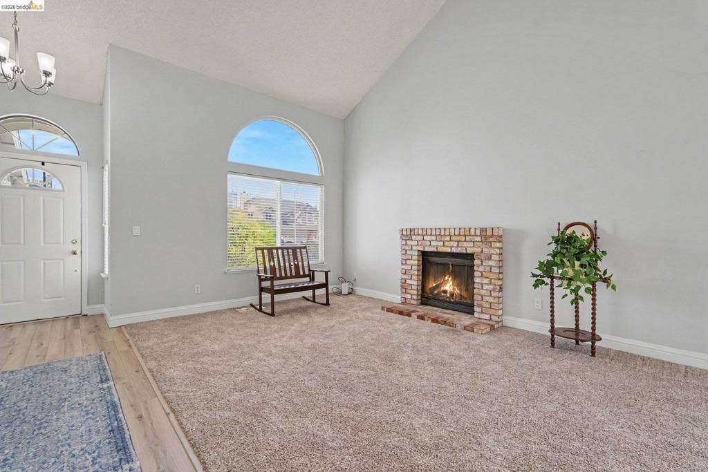 304 Greystone Dr, Antioch, CA 94509 Vaulted ceilings, brick fireplace with a raised hearth, arched window, and overhead chandelier