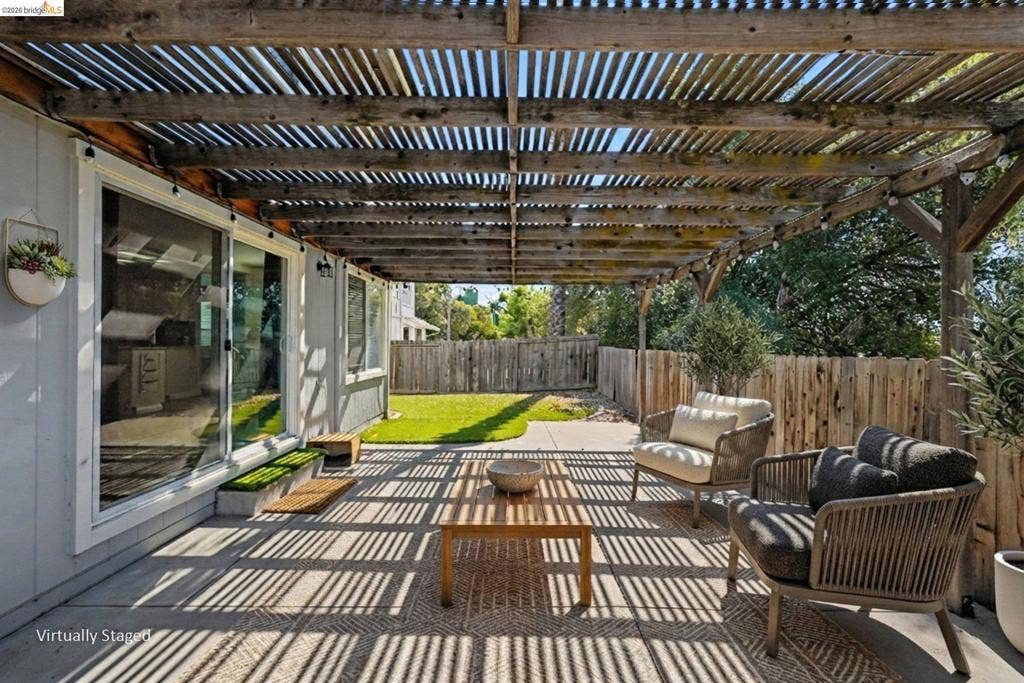 304 Greystone Dr, Antioch, CA 94509 Covered patio featuring a timber pergola, concrete flooring, large sliding glass doors, and a wood privacy fence