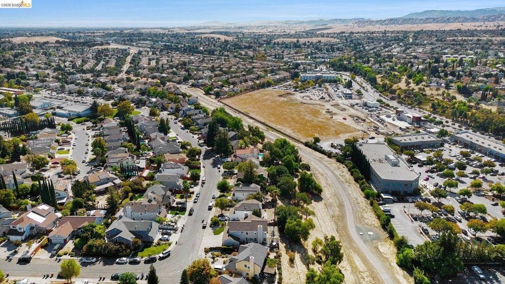 304 Greystone Dr, Antioch, CA 94509 Aerial perspective featuring a multi-layered residential community with extensive mature landscaping and distant mountain topography
