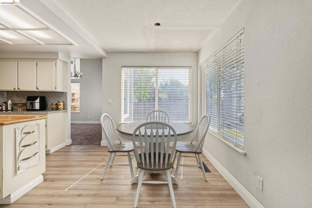 304 Greystone Dr, Antioch, CA 94509 Kitchen area featuring light-toned cabinetry, wood-finish flooring, recessed lighting, and large windows with horizontal blinds