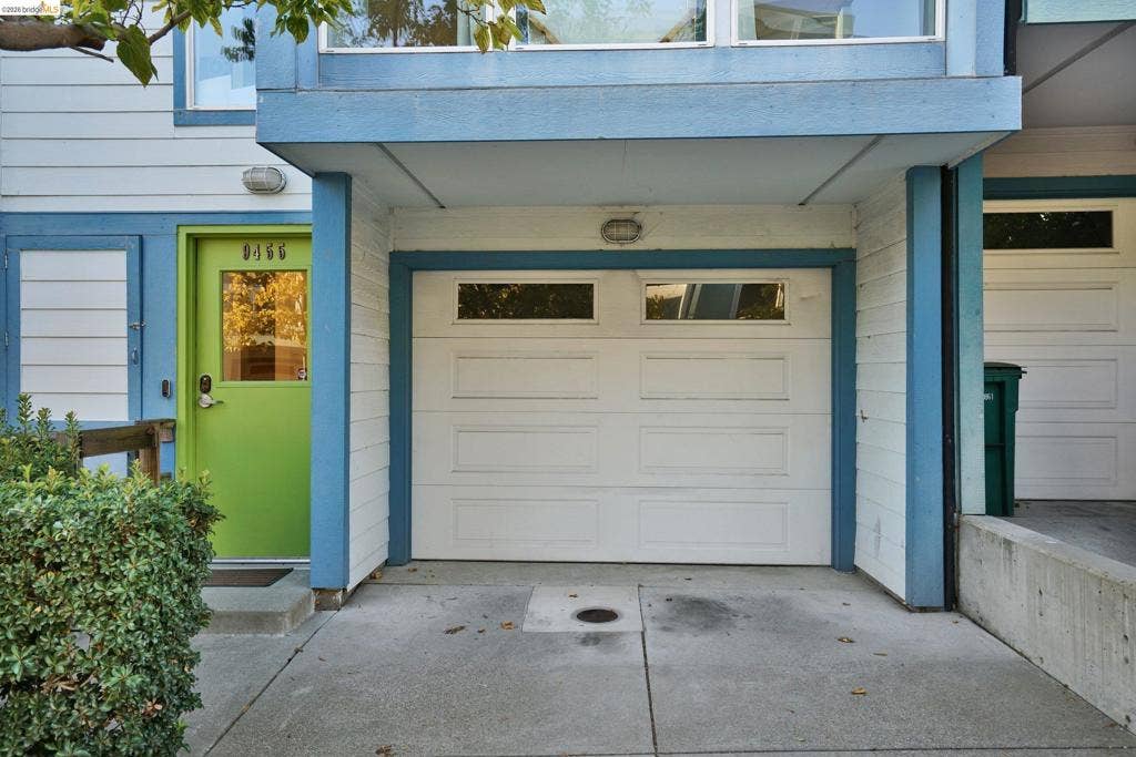 Exterior facade featuring white horizontal siding, an attached garage with window inserts, and a lime green entryway door