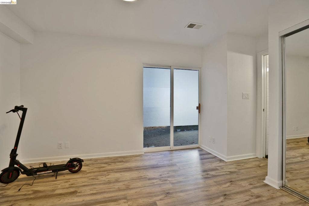 Interior space featuring wood-finish flooring, sliding glass door, and closet with mirrored sliding doors