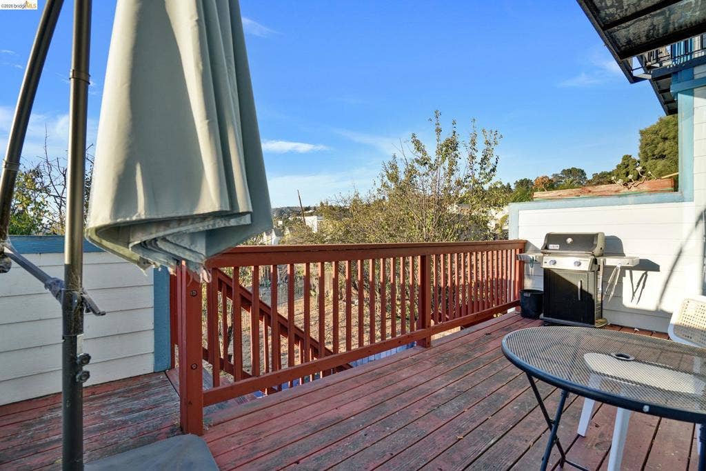 Elevated wooden deck featuring horizontal plank flooring, a red-painted wood balustrade, and horizontal siding