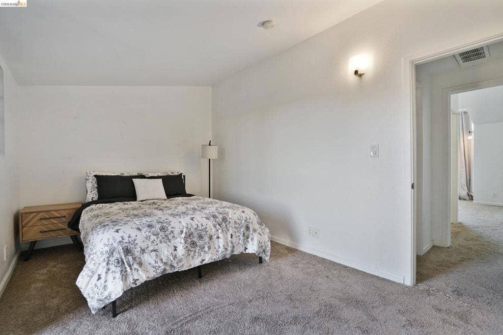 Neutral wall finishes, plush carpeting, and wall-mounted light fixture