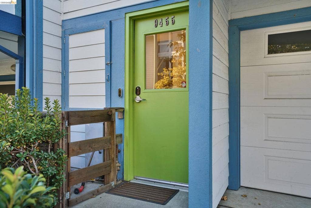 Entryway featuring horizontal lap siding, a vibrant lime green door with a glass inset, metal hardware, and an attached garage door with a rectangular window