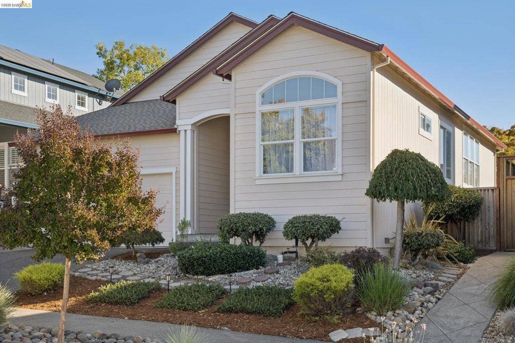 5503 Rainbow Cir, Santa Rosa, CA 95409 Single-story residence featuring horizontal lap siding, a covered entryway, an arched window, a multi-gabled roofline, and landscaped rock-mulch front yard
