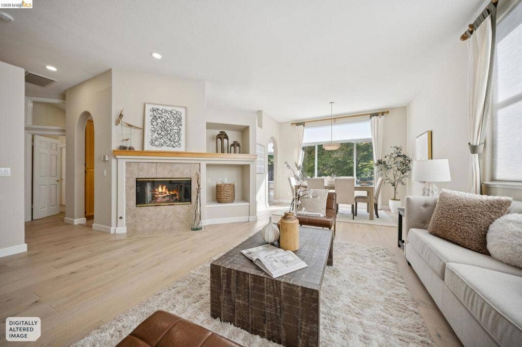 5503 Rainbow Cir, Santa Rosa, CA 95409 Living area featuring wood-finish flooring, a tile-surround fireplace, built-in shelving, arched doorway detailing, and recessed lighting