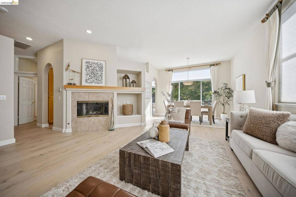 5503 Rainbow Cir, Santa Rosa, CA 95409 Open-concept living area featuring wood-finish flooring, recessed lighting, arched doorways, a tile-surround fireplace with a wood mantel, and built-in display shelving