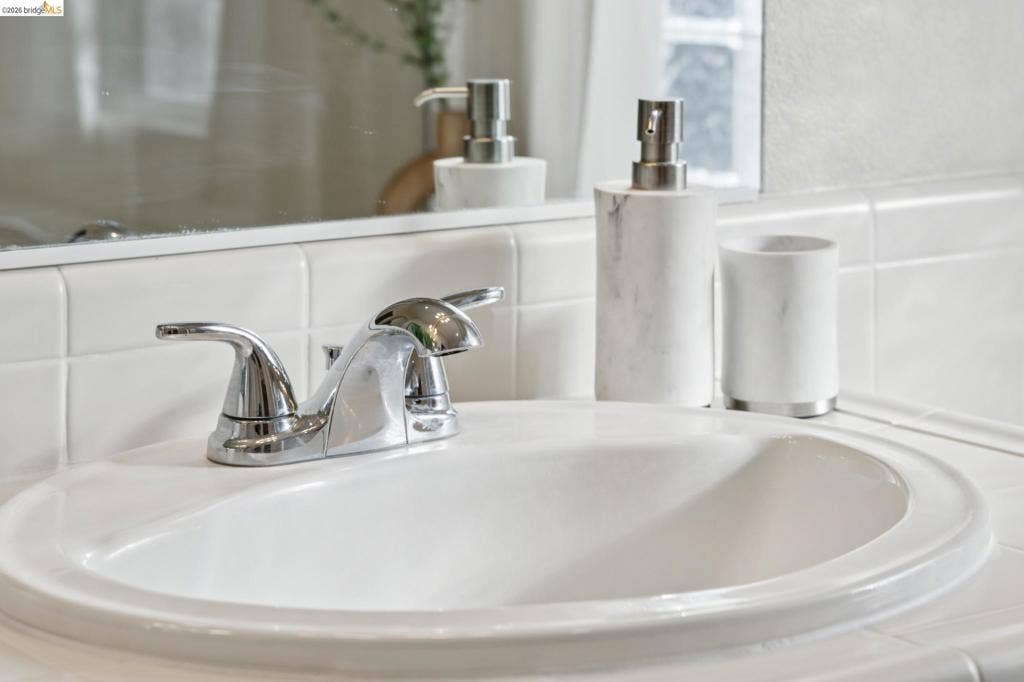 5503 Rainbow Cir, Santa Rosa, CA 95409 Inset porcelain sink with polished chrome double-handle faucet, integrated tile countertop, and flat-panel wall mirror