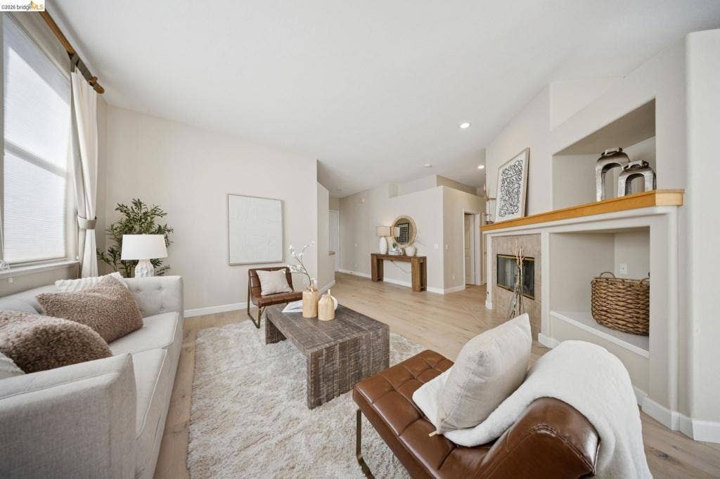 5503 Rainbow Cir, Santa Rosa, CA 95409 Living space featuring vaulted ceilings, light-toned wood-finish flooring, a tile-surround fireplace, and built-in shelving with wood mantel detailing