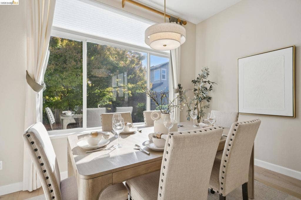5503 Rainbow Cir, Santa Rosa, CA 95409 Large multi-pane window with a neutral pleated shade, three-tier drum pendant light fixture, and wood-finish flooring