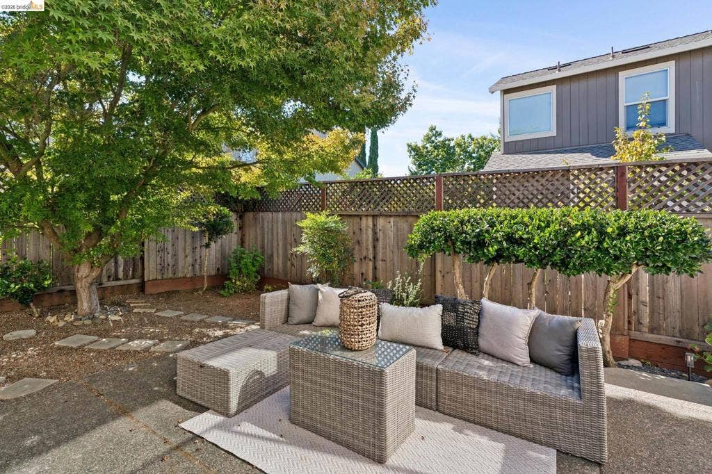 5503 Rainbow Cir, Santa Rosa, CA 95409 Rear courtyard featuring a concrete patio, decorative wood lattice fencing, mature tree canopy, and stone pavers