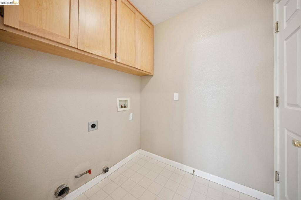 5503 Rainbow Cir, Santa Rosa, CA 95409 Utility area featuring light-finish wood cabinetry, tiled flooring, and designated washer and dryer hookups
