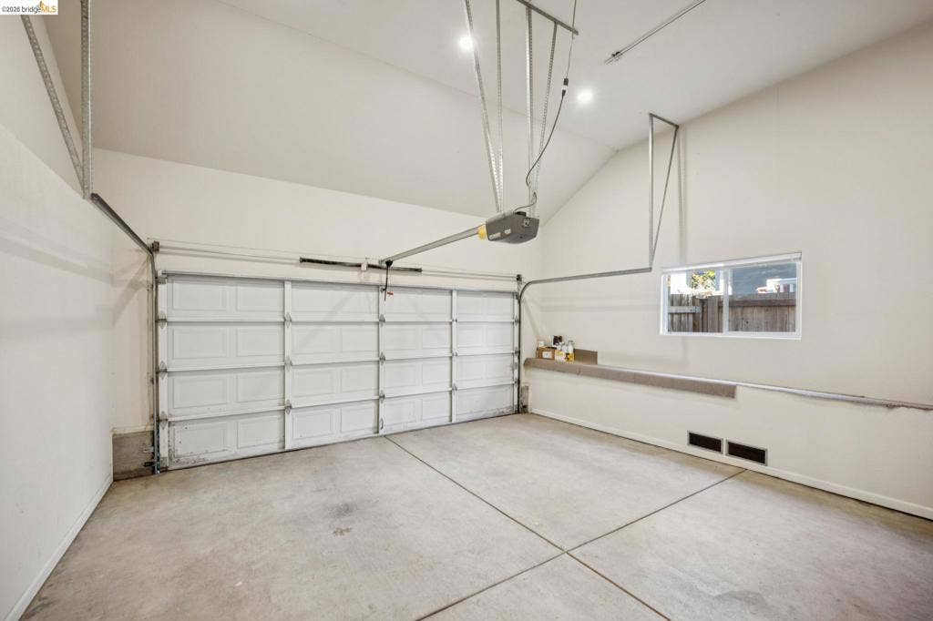 5503 Rainbow Cir, Santa Rosa, CA 95409 Garage space featuring high vaulted ceilings, a concrete floor, a white sectional garage door, and a horizontal window
