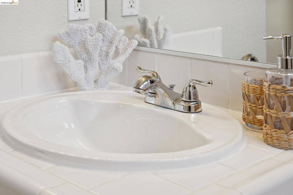 5503 Rainbow Cir, Santa Rosa, CA 95409 White tile countertop with integrated porcelain drop-in sink, chrome double-handle faucet, and full-width vanity mirror