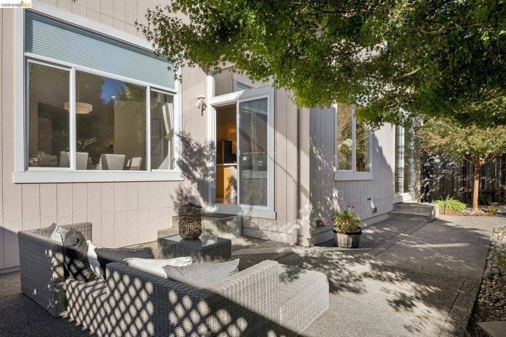 5503 Rainbow Cir, Santa Rosa, CA 95409 Exterior patio featuring a concrete surface, vertical wood siding, expansive multi-pane windows, and a sliding glass door