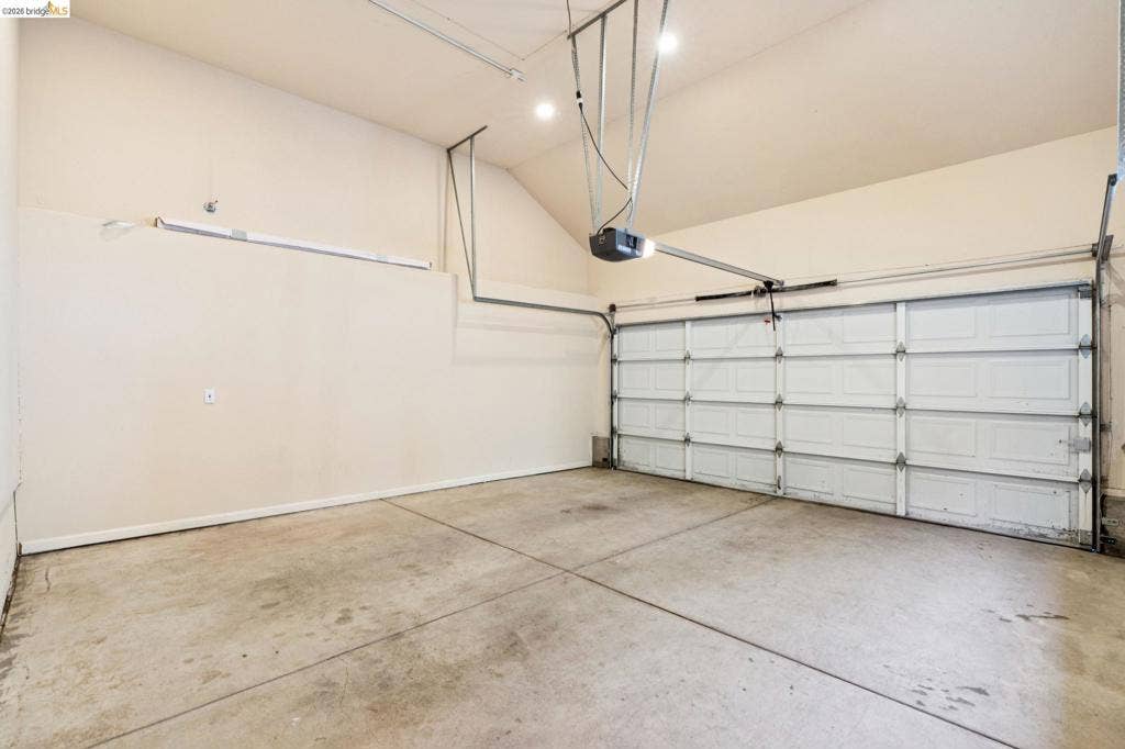 5503 Rainbow Cir, Santa Rosa, CA 95409 Attached garage featuring high vaulted ceilings, concrete flooring, recessed lighting, and a multi-panel overhead door with an automatic opener