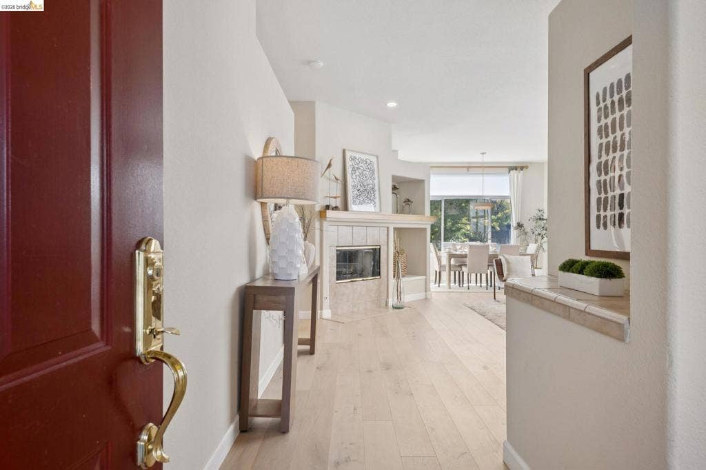 5503 Rainbow Cir, Santa Rosa, CA 95409 Entryway featuring wood-finish flooring, a fireplace with stone surround, a wood-finish mantel, and integrated shelving
