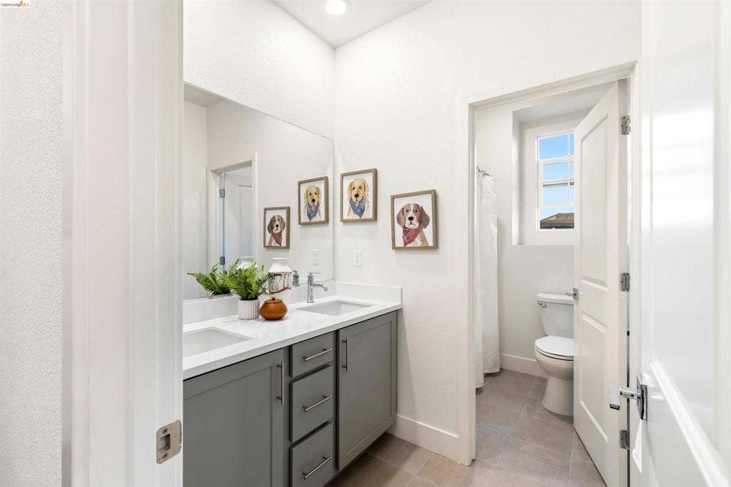 539 Gemstone Way, Oakley, CA 94561 Dual-sink vanity with quartz countertop, grey cabinetry, oversized wall-mounted mirror, and tile flooring