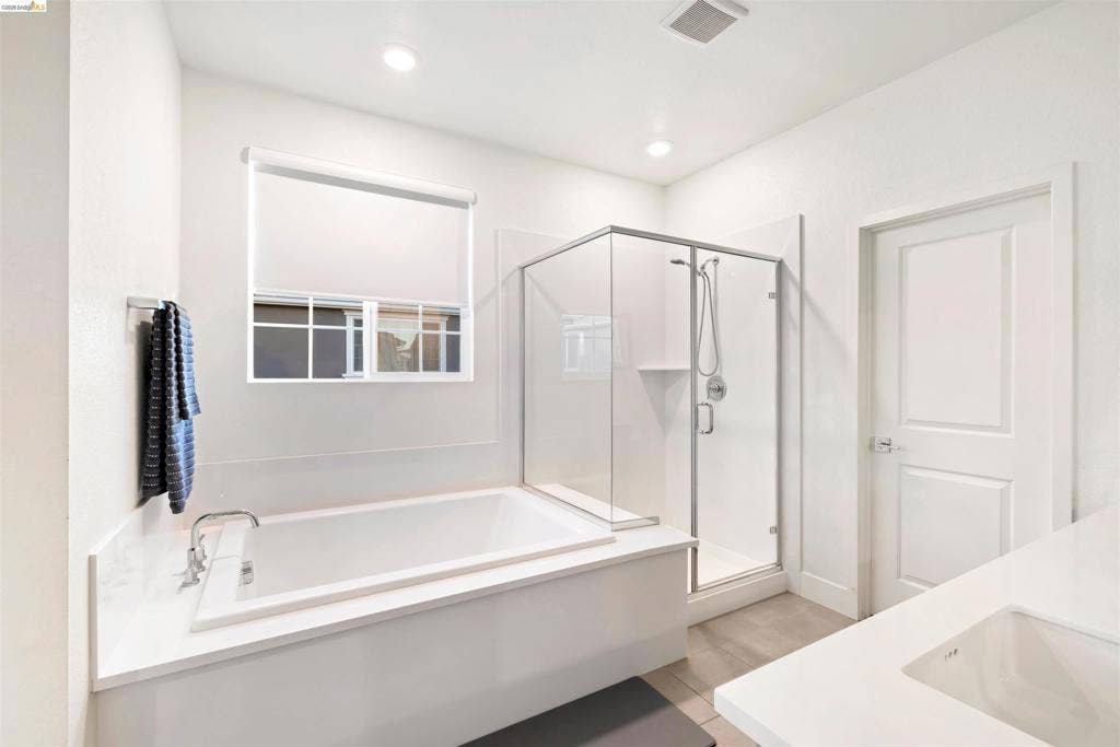 539 Gemstone Way, Oakley, CA 94561 Bathroom featuring a deep soaking tub with a surrounding solid-surface deck, a glass-enclosed walk-in shower, recessed lighting, and a white vanity with an integrated basin