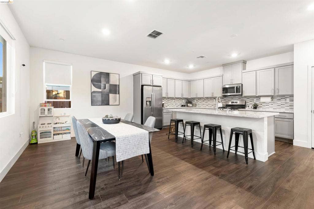 539 Gemstone Way, Oakley, CA 94561 Kitchen featuring stone countertops, an expansive center island, stainless steel appliances, shaker-style cabinetry, and wood-finish flooring