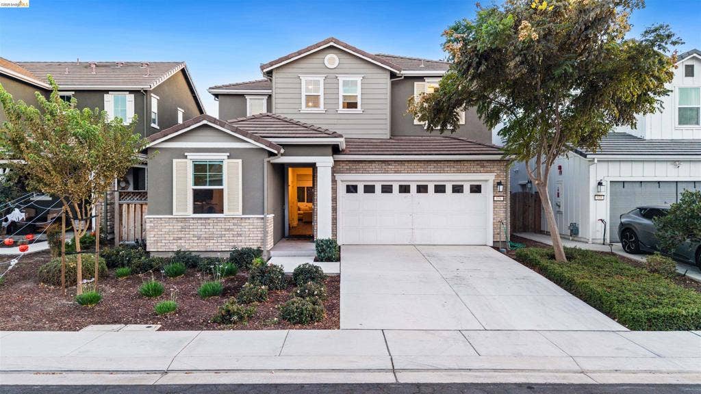 539 Gemstone Way, Oakley, CA 94561 Two-story exterior featuring a mix of horizontal siding and stone veneer, a concrete driveway, an attached two-car garage with windows, and decorative shutters