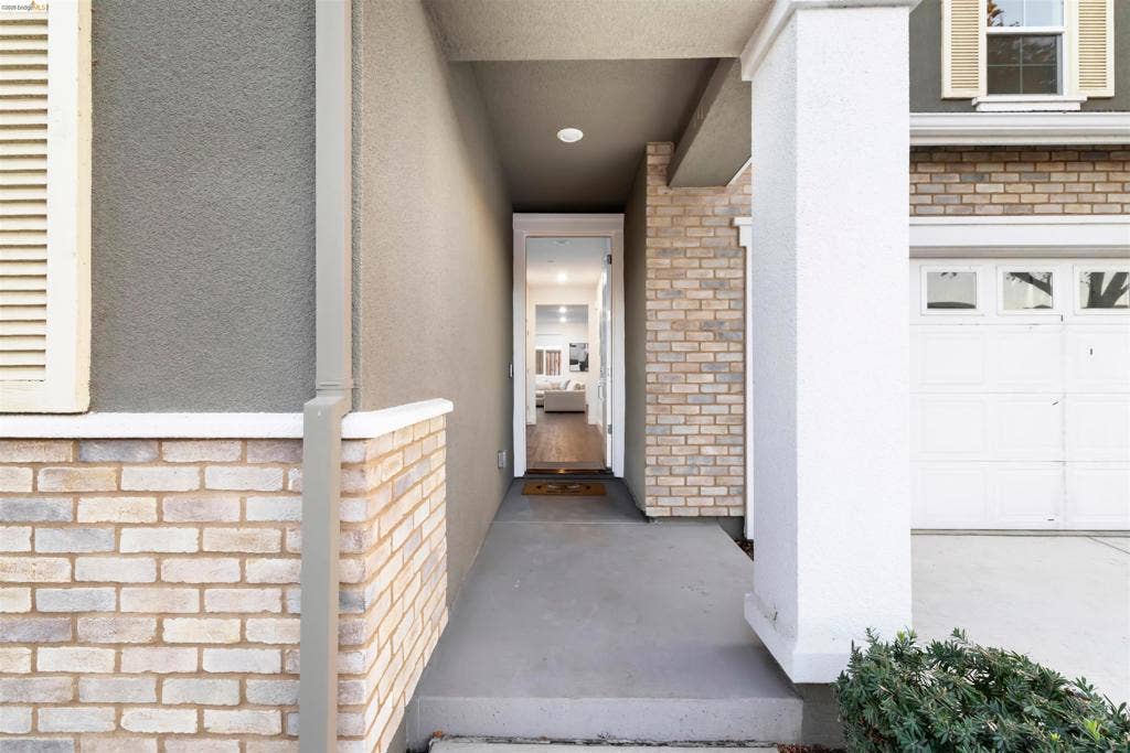 539 Gemstone Way, Oakley, CA 94561 Covered entryway featuring a concrete porch, brick veneer accents, recessed ceiling lighting, and a paneled garage door