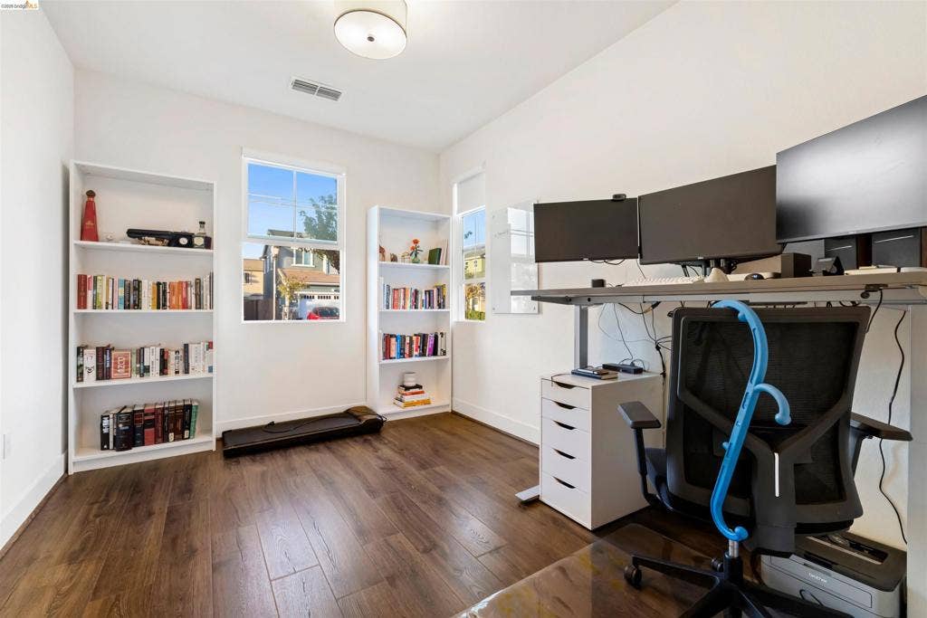 539 Gemstone Way, Oakley, CA 94561 Room featuring wood-finish flooring, dual built-in floor-to-ceiling shelving units, and two windows providing natural light, finished with a central flush-mount ceiling fixture