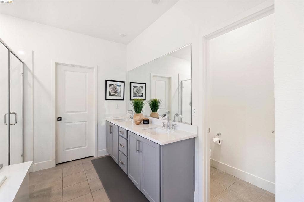 539 Gemstone Way, Oakley, CA 94561 Dual-sink vanity with gray cabinetry, white countertops, full-width wall mirror, and neutral tile flooring