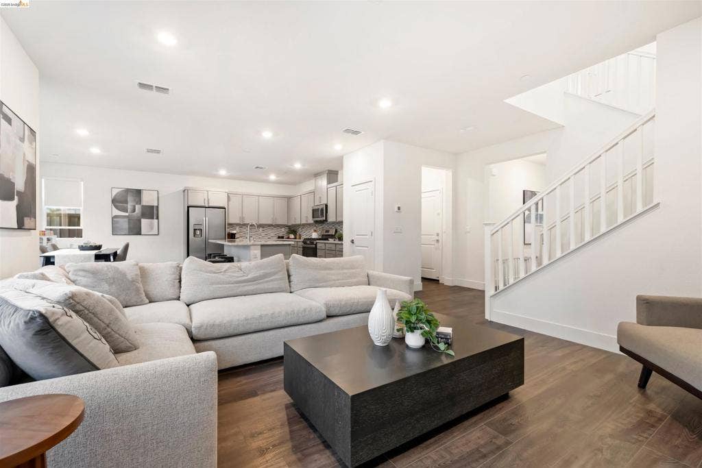539 Gemstone Way, Oakley, CA 94561 Open-concept interior featuring wood-finish flooring, recessed lighting, a staircase with white balusters, and a kitchen with grey cabinetry and stone-look countertops