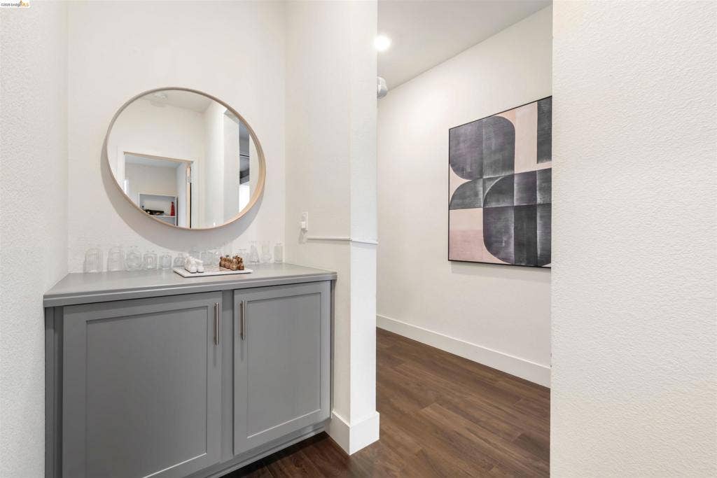 539 Gemstone Way, Oakley, CA 94561 Custom cabinetry featuring soft-gray finish, recessed-panel doors, sleek metallic hardware, and a round wall-mounted mirror over wood-finish flooring