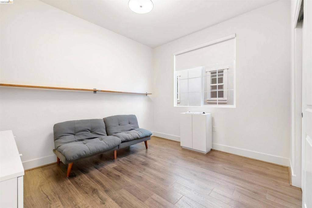 539 Gemstone Way, Oakley, CA 94561 Interior space featuring wood-finish flooring, white walls, a mounted horizontal handrail, a single-pane window with a roller shade, and a flush-mount overhead light fixture