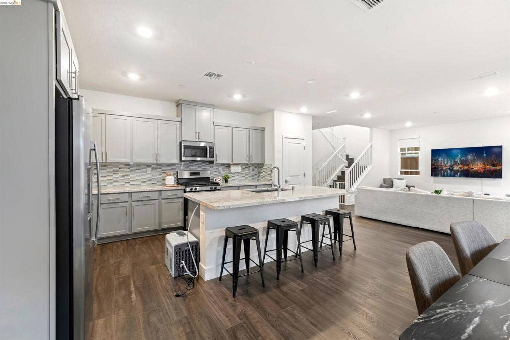 539 Gemstone Way, Oakley, CA 94561 Kitchen featuring shaker-style cabinetry, stone countertops, a multi-tonal glass tile backsplash, stainless steel appliances, and wood-finish flooring