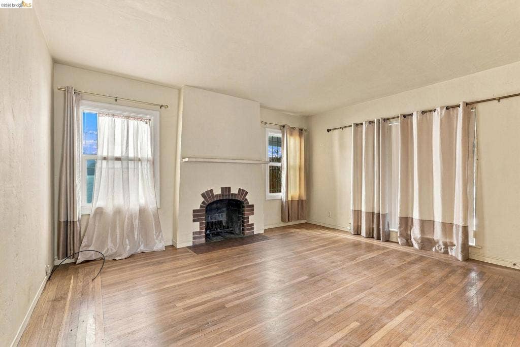 2901 Sheffield Ave, Oakland, CA 94602 Wood-finish flooring, masonry fireplace with arched detailing, mantel shelf, and multiple windows