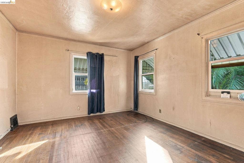 2901 Sheffield Ave, Oakland, CA 94602 Bedroom featuring wood-finish flooring, two windows with exterior roof overhangs, and a ceiling-mounted light fixture