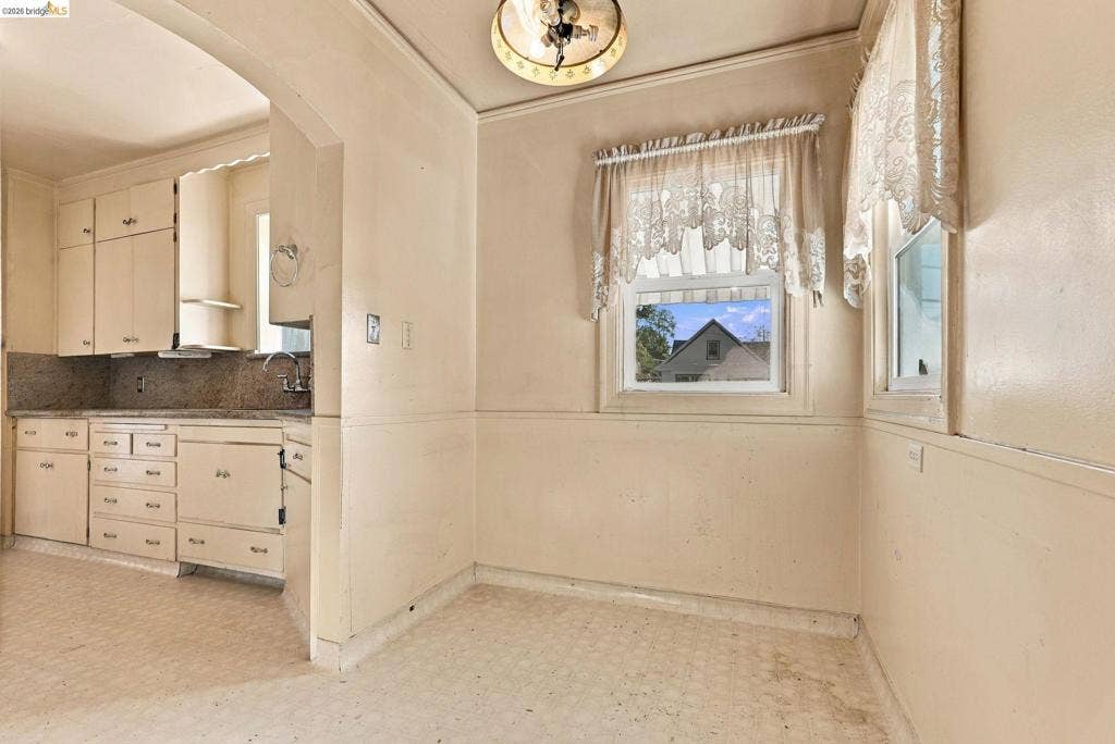 2901 Sheffield Ave, Oakland, CA 94602 Kitchen featuring custom cabinetry, stone countertops, integrated hardware, double-window configuration, and an arched architectural opening