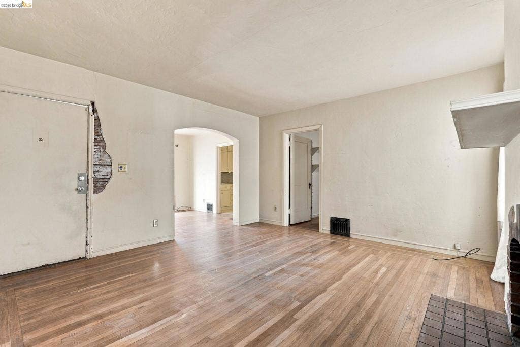 2901 Sheffield Ave, Oakland, CA 94602 Interior room featuring wood-finish flooring, a masonry hearth, and an arched passageway