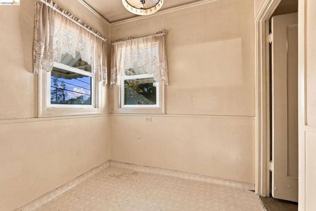 2901 Sheffield Ave, Oakland, CA 94602 Interior space featuring chair rail molding, two multi-pane windows with trim, a central semi-flush mount light fixture, and resilient flooring