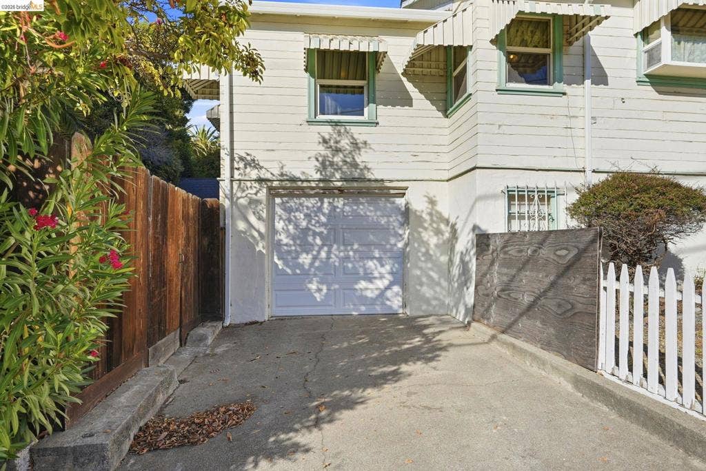 2901 Sheffield Ave, Oakland, CA 94602 Exterior facade featuring white horizontal siding, a single-car garage, fixed window awnings, and a concrete driveway