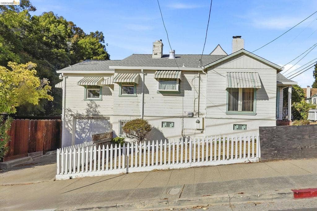 2901 Sheffield Ave, Oakland, CA 94602 Exterior featuring horizontal siding, multiple windows with metal awnings, an integrated garage and a white picket fence