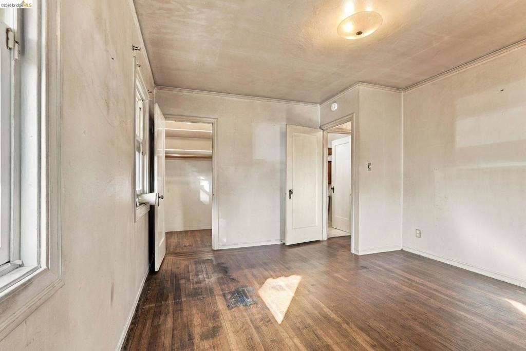 2901 Sheffield Ave, Oakland, CA 94602 Room featuring wood-finish flooring, two solid-core interior doors, recessed closet storage with built-in shelving, and a central ceiling-mounted light fixture