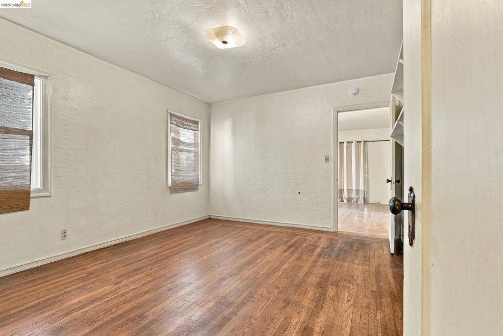 2901 Sheffield Ave, Oakland, CA 94602 Bedroom featuring wood-finish flooring, textured walls, dual windows, and built-in shelving