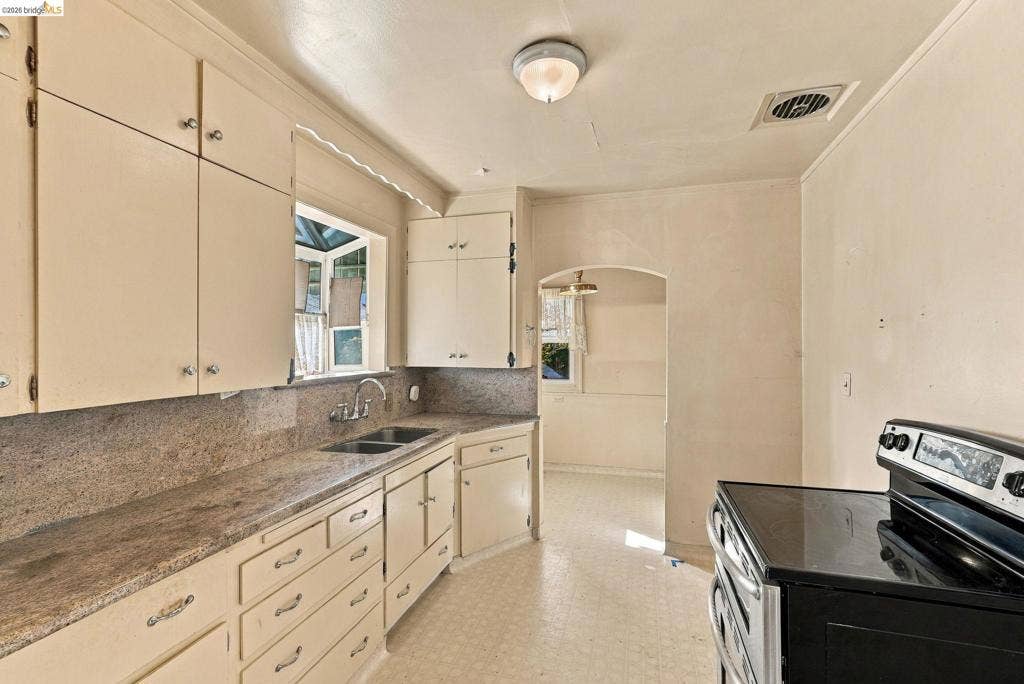 2901 Sheffield Ave, Oakland, CA 94602 Kitchen featuring solid-surface countertops, dual-basin sink, overhead cabinetry, and integrated stove